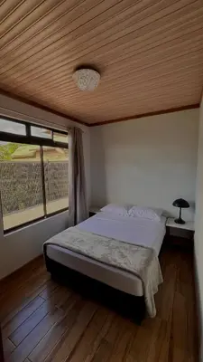 a bedroom with a bed with a wooden ceiling at Arenal Stone House in Ángeles