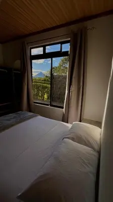 a bedroom with a bed and a window with a view at Arenal Stone House in Ángeles