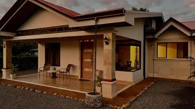 a small house with a porch with a table at Arenal Stone House in Ángeles