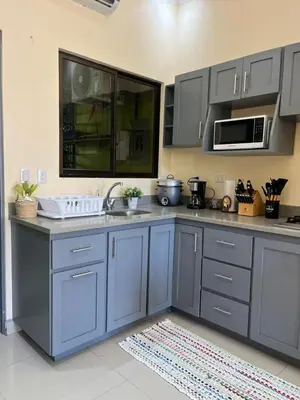 a kitchen with blue cabinets and a microwave at House equipped with a Jacuzzi in Quepos in Quepos