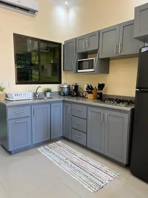 a kitchen with blue cabinets and a black refrigerator at House equipped with a Jacuzzi in Quepos in Quepos