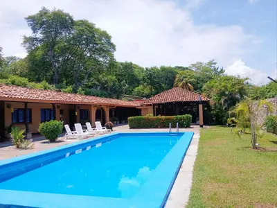 a swimming pool in front of a house at Naranjo Easy Lodge in Paquera