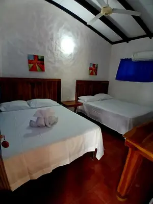 two beds in a room with two white beds at Naranjo Easy Lodge in Paquera
