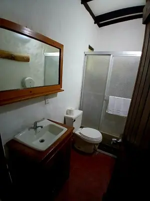 a bathroom with a sink and a toilet and a mirror at Naranjo Easy Lodge in Paquera