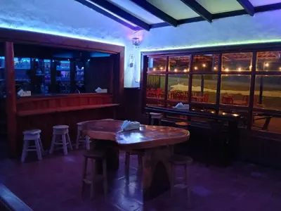 a bar with a wooden table and some stools at Naranjo Easy Lodge in Paquera