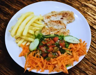 a plate of food with french fries and vegetables at Naranjo Easy Lodge in Paquera
