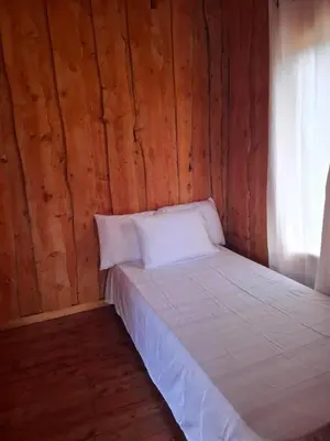 a bed in a room with a wooden wall at Cabaña Montaña Serena in El Copey