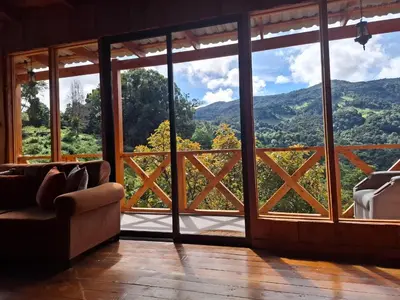 a living room with a large window with a view at Cabaña Montaña Serena in El Copey
