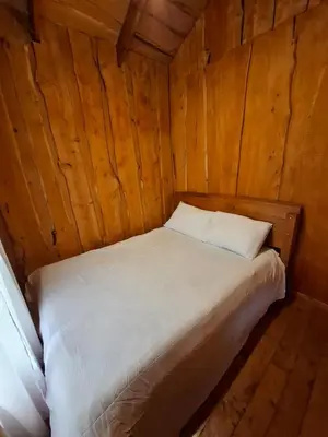 a bed in a cabin with a wooden wall at Cabaña Montaña Serena in El Copey