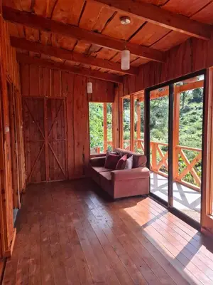 a living room with a couch in a room with windows at Cabaña Montaña Serena in El Copey