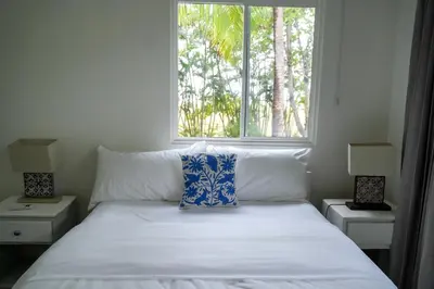a bedroom with a bed with a window and two lamps at Beachfront Bliss Steps to the beach in Playa Azul