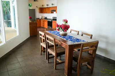 a kitchen with a wooden table and chairs with flowers on it at Beachfront Bliss Steps to the beach in Playa Azul