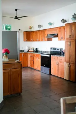 a kitchen with wooden cabinets and a stove top oven at Beachfront Bliss Steps to the beach in Playa Azul