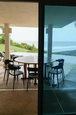 a table and chairs on a patio with a view of the ocean at Beachfront Bliss Steps to the beach in Playa Azul
