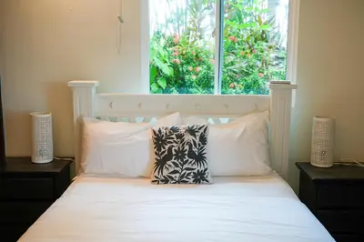 a bedroom with a bed with white pillows and a window at Beachfront Bliss Steps to the beach in Playa Azul