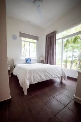 a bedroom with a large white bed with a window at Beachfront Bliss Steps to the beach in Playa Azul