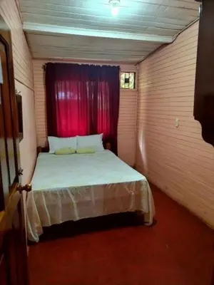 a small room with a bed with a red curtain at Corozalito Turtle Lodge in Corozalito