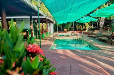 a pool with blue umbrellas next to a building at Corozalito Turtle Lodge in Corozalito