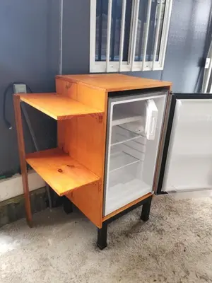 a wooden cabinet with an open door next to a refrigerator at Cabinas Pacific Breeze in Parrita