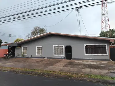 a white building with a parking lot in front of it at Casa Vacacional Brisas del Volcán Miravalles in Hacienda Guayabo