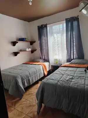 a bedroom with two beds and a window with curtains at Casa Vacacional Brisas del Volcán Miravalles in Hacienda Guayabo