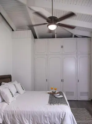 a bedroom with a white bed with a ceiling fan at Green villa in La Asunción