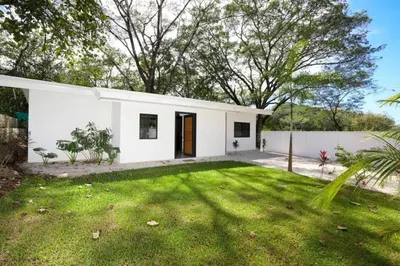 a white house with a green yard at Casa Abana in Sámara