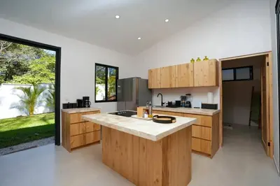 a kitchen with wooden cabinets and a large window at Casa Abana in Sámara