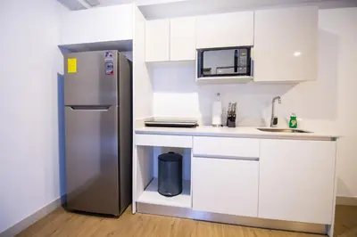 a small kitchen with a refrigerator and a counter at Apartamento Moderno con Vista Piscina Infinita Secrt Escalante in San Pedro