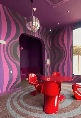 a room with red chairs and a table and a purple wall at Apartamento Moderno con Vista Piscina Infinita Secrt Escalante in San Pedro