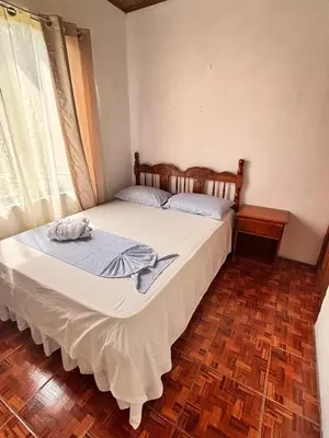 a bedroom with a large bed with white sheets at Casa Sueño Verde, Juanilama De Pocosol in Muelle del Arenal