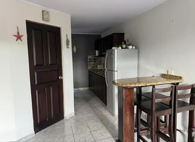 a kitchen with a white refrigerator and a table at Apartamento Jaco Park,Jaco in Jacó