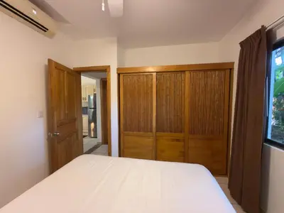 a bedroom with a white bed and wooden cabinets at Lavinia Apartment Playa Potrero in Potrero