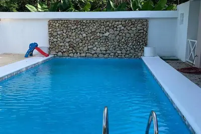 a swimming pool with blue water and a stone wall at Apartamento Manzu in Santa Cruz