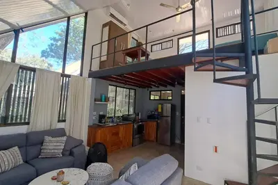 a living room with a blue couch and a spiral staircase at Cozy Jungle Loft Close to Tamarindo and Surf Beaches in Santa Rosa