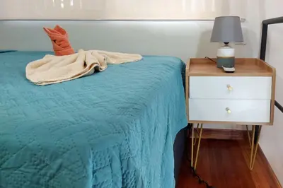 a bed with a blue blanket next to a night stand at Cozy Jungle Loft Close to Tamarindo and Surf Beaches in Santa Rosa