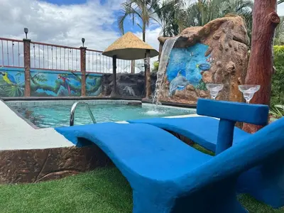 a pool with a waterfall and a blue chair in front at Spring House in Ángeles
