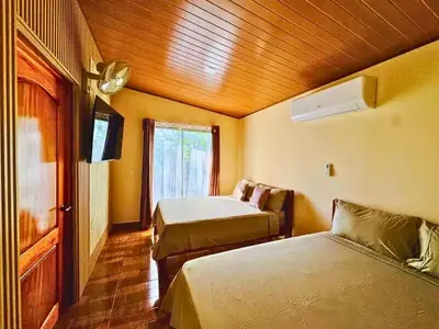 a hotel room with two beds and a window at Rio Celeste Birds Garden Apartment with Air Conditioning Comfort and Privacy in a Natural Environment 3 in Upala