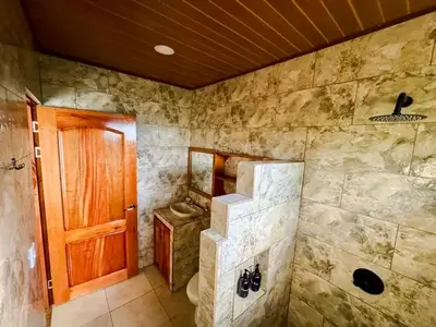 a bathroom with a toilet and a wooden door at Rio Celeste Birds Garden Apartment with Air Conditioning Comfort and Privacy in a Natural Environment 3 in Upala