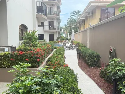 a walkway between two buildings with benches and flowers at Monaco Condominiums Unit 7 Luxury Pool View Condo 3BR 2BA - Walk to the Beach, Shopping, Tours in Jacó