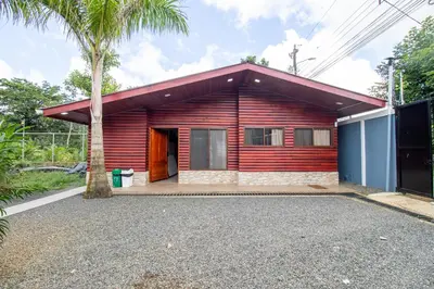 a red house with a palm tree in front of it at Cabaña Refugio Verde Arenal in Fortuna