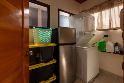 a kitchen with a refrigerator and a washer and dryer at Cabaña Refugio Verde Arenal in Fortuna