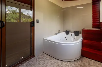 a bath tub in a bathroom with a shower at Cabaña Refugio Verde Arenal in Fortuna
