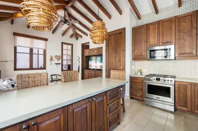 a kitchen with wooden cabinets and a stove top oven at Bright Modern Home with Beach Club Access and Walking Distance to the Beach in Playa Danta