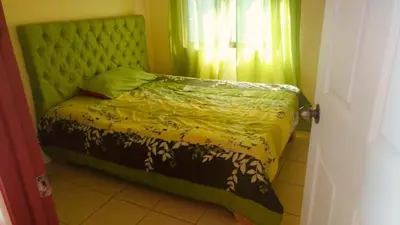 a bedroom with a bed with a green headboard and a window at Casa para vacacionar Orotina in Orotina