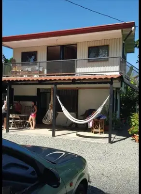 a woman sitting on the porch of a house with a hammock at Casa Elenia in Bahia