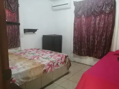 a room with a bed and two windows with curtains at Casa Elenia in Bahia