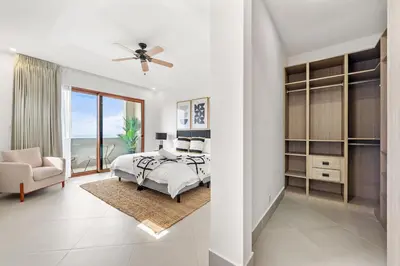 a white bedroom with a bed and a chair at Panaromic Oceanview Luxury 3BR Private Rooftop in Tamarindo