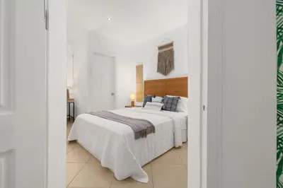 a white bedroom with a large white bed with blue pillows at Peaceful 2BR Retreat w Pool - Near CR Best Beaches in Matapalo
