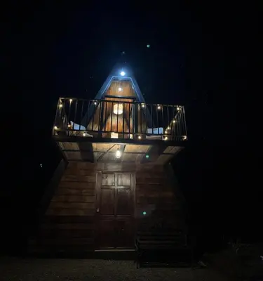 a wooden lighthouse with a deck at night at Cabaña La paz in Alajuela City